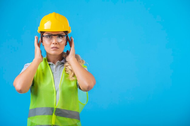 Female engineer in yellow helmet and gear wearing preventive eyeglasses. 