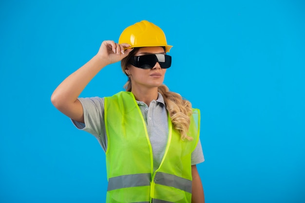 Ingegnere femminile in casco giallo e attrezzi che indossano occhiali preventivi a raggi e si sentono sicuri.