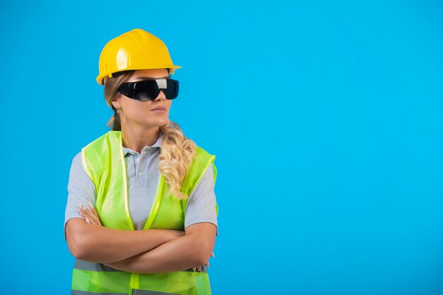 노란색 헬멧 및 장비 전문가로 위장 해 광선 예방 안경을 착용하는 여성 엔지니어.