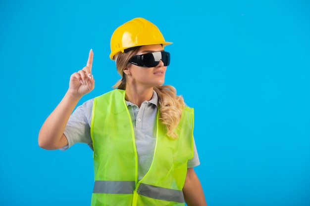 光線予防眼鏡をかけている黄色いヘルメットとギアの女性エンジニア