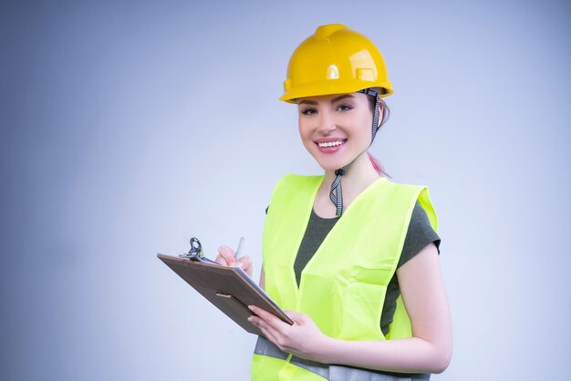 Female engineer in a yellow helmet smiles