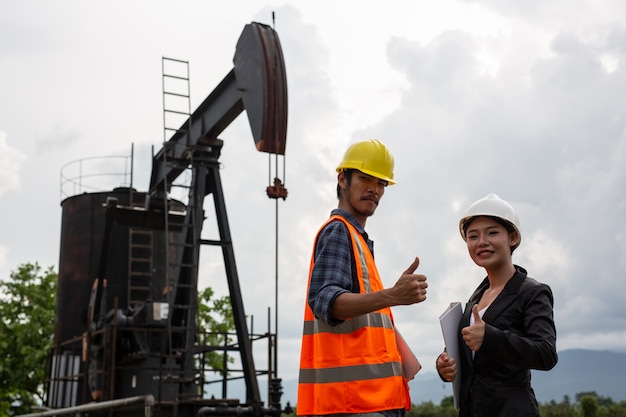 Free photo female engineers consult with workers next to working oil pumps with a sky .