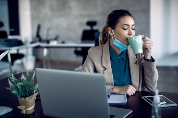 Женщина-предприниматель наслаждается чашкой свежего кофе в офисе