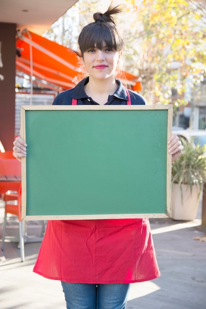 屋外のcaf atで空の緑のメニューボードを保持している女性起業家