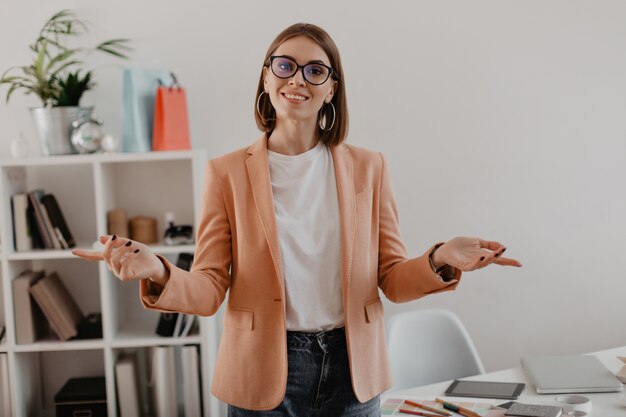 Female entrepreneur in pink jacket with smile in white spacious office.