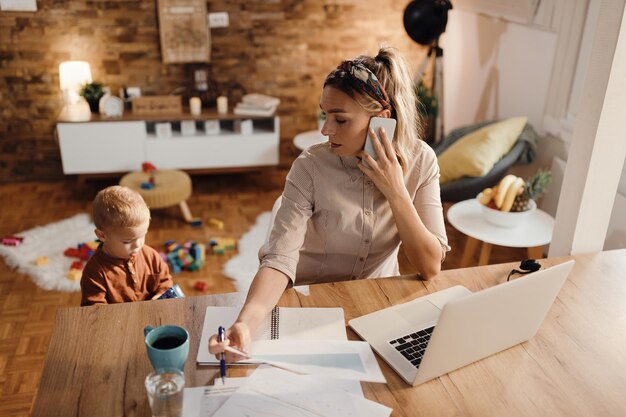 Female entrepreneur talking on the phone while being with her son at home