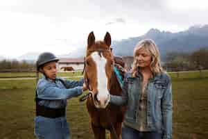 Free photo female equestrian instructor teaching child how to ride horse