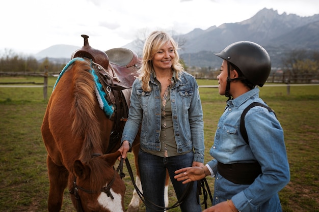 Free photo female equestrian instructor teaching child how to ride horse