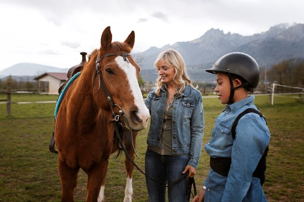 Female equestrian instructor teaching child how to ride horse