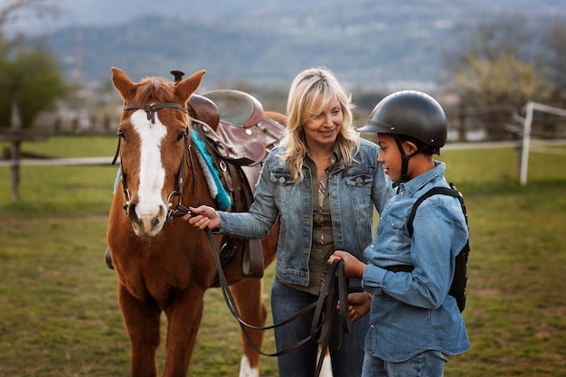 Istruttore equestre femminile che insegna al bambino come andare a cavallo