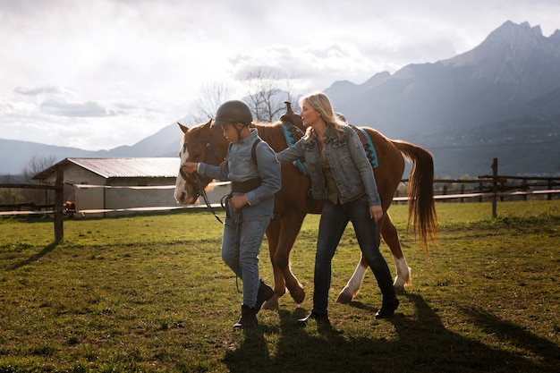 Foto gratuita istruttore equestre femminile che insegna al bambino come andare a cavallo