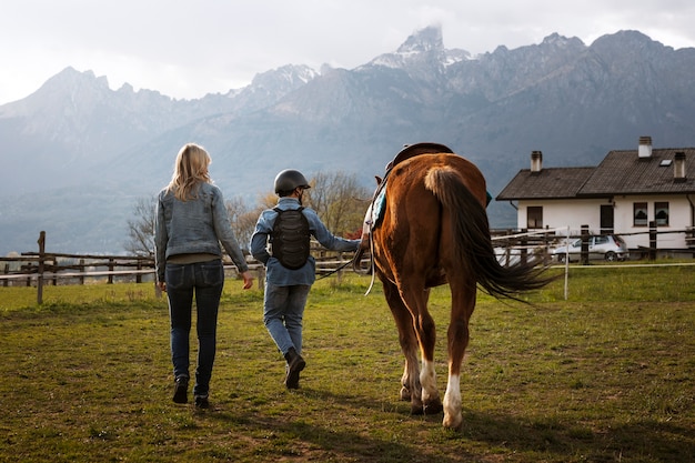 Female equestrian instructor teaching child how to ride horse