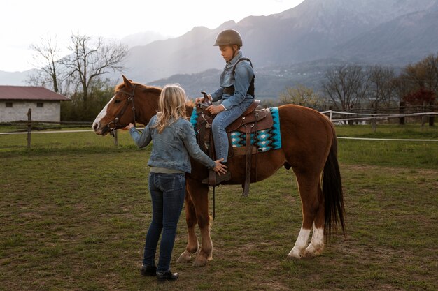 子供に馬の乗り方を教える女性馬術インストラクター