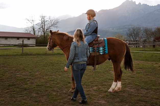 子供に馬の乗り方を教える女性馬術インストラクター