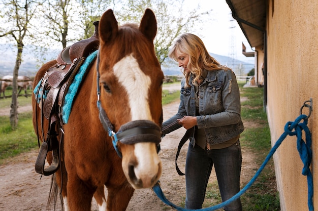 Бесплатное фото Женский инструктор по конному спорту с лошадью