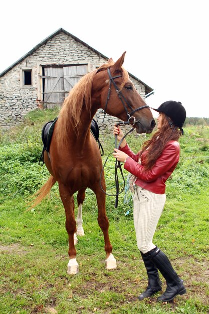 茶色の馬を持つ女性乗馬