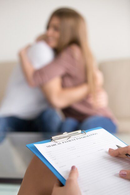 Female family psychologist filling information about couple in medical card