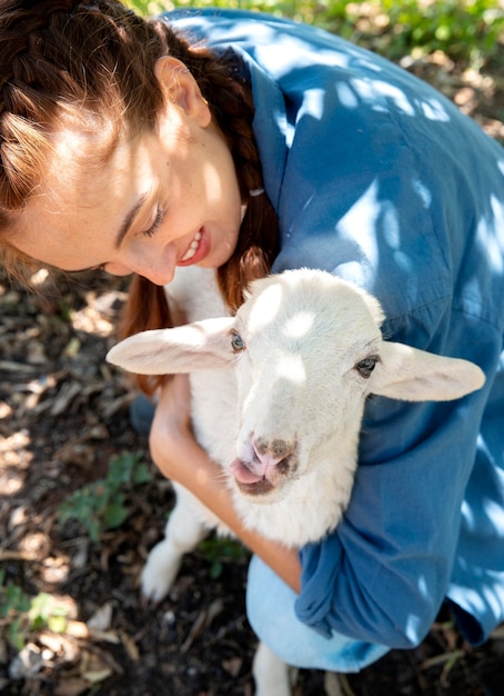 Contadina che tiene in braccio un cucciolo di pecora