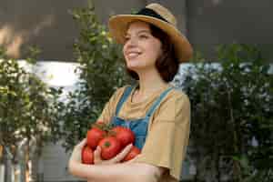 Free photo female farmer holding some tomatoes