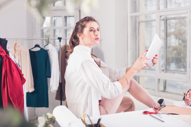 La stilista femmina che lavora in studio seduto sulla scrivania