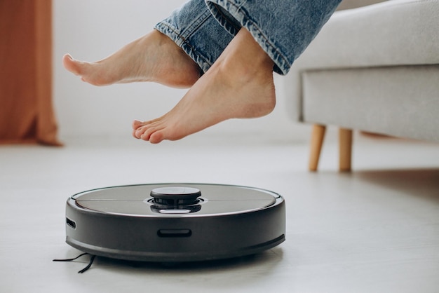 Female feet over the rechargeable vacuum cleaner