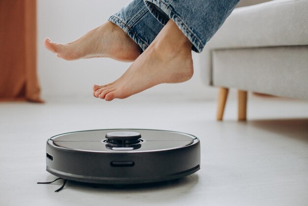 Female feet over the rechargeable vacuum cleaner