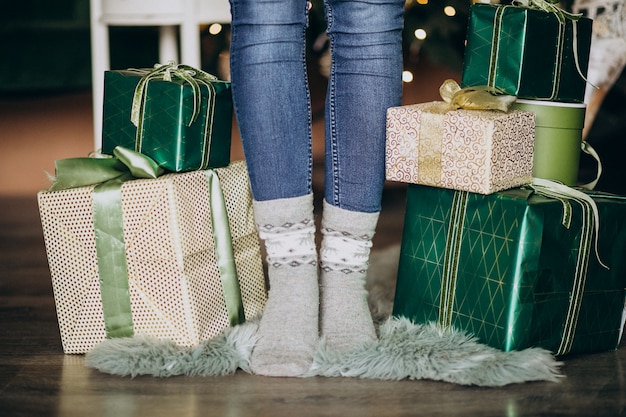 Женские ноги в носках с рождественским подарком вокруг
