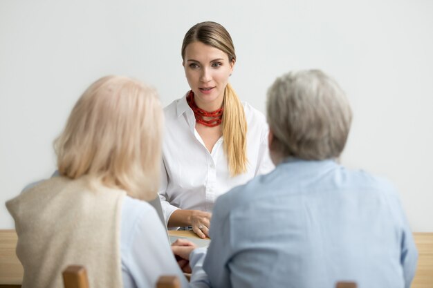 Female financial advisor talking consulting senior aged couple at meeting