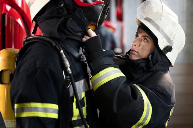 Female firefighter adjusting her colleague's fire mask