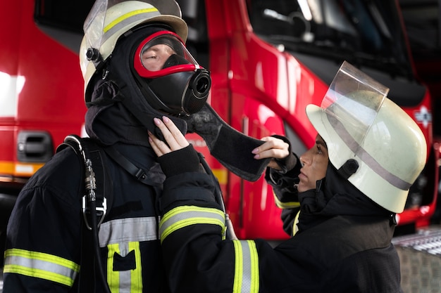 無料写真 同僚の防火マスクを調整する女性消防士