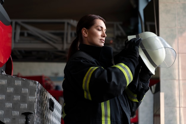 Free photo female firefighter putting on safety helmet
