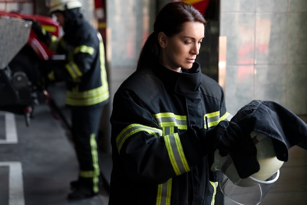 Female firefighter putting on safety helmet