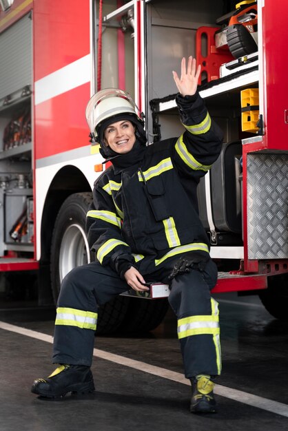 Female firefighter at station equipped with suit and safety helmet