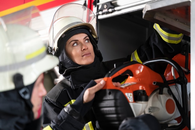 Female firefighter at station equipped with suit and safety helmet
