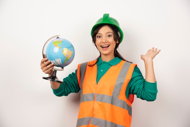 Free photo female firefighter with globe feeling happy on white background.