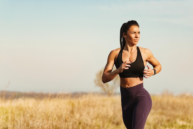 Female fitness instructor jogging during sports training in nature Copy space