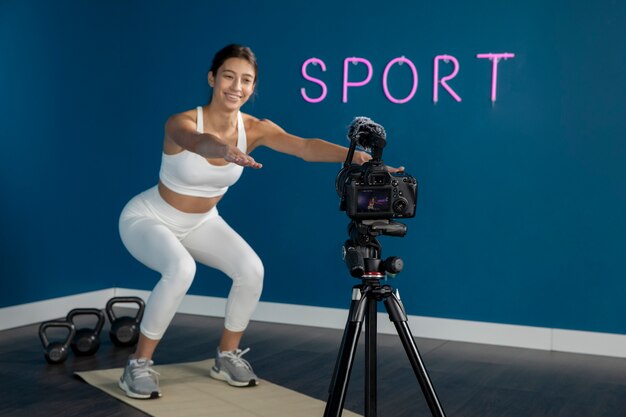 Female fitness instructor teaching a class at home while using camera on tripod