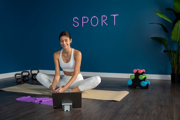 Female fitness instructor using tablet to teach a class from home