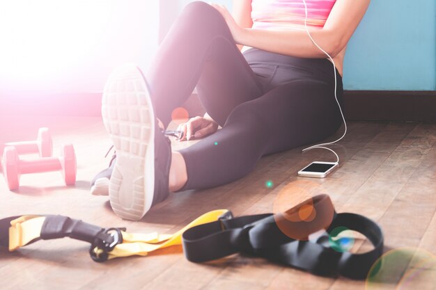 Female fitness resting and relaxing after workout. Woman sitting down on wood floor. Sport, Fitness, Healthy lifestyle concept