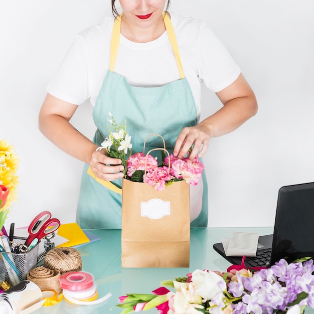 紙袋に花を並べる女性の花屋