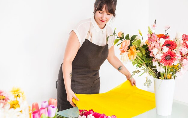 Female florist arranging yellow cloth for making flower bouquet