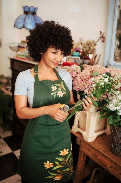 Female florist cutting stem of flowers with secateurs