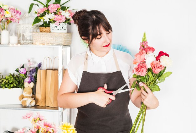 Female florist cutting twigs of flowers with scissors