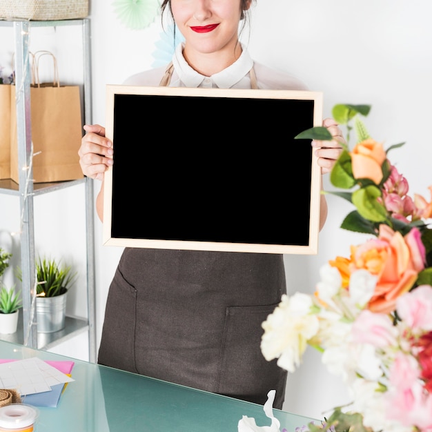 Female florist with blank slate in floral shop