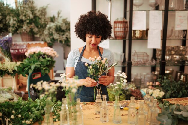 Female florist with bunch of flowers standing in shop