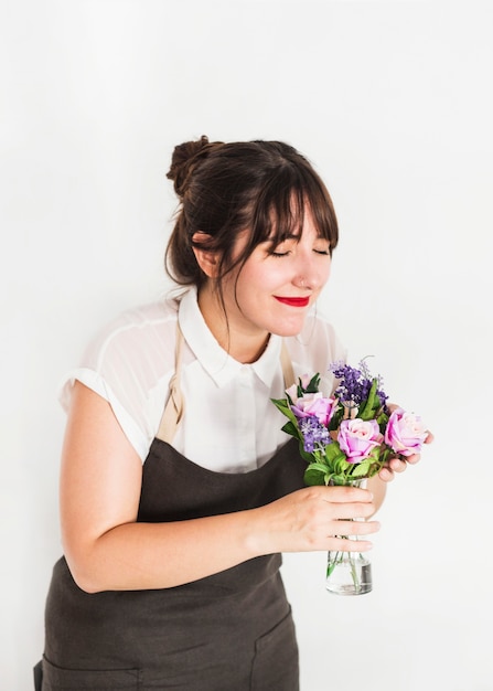 Female florist with eyes closed smelling flowers in vase