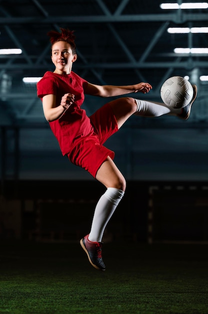 Free photo female football player kicking ball