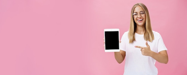 Free photo female freelance programmer proudly showing her app for digital tablet holding gadget pointing at de