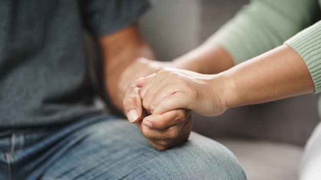 여성 친구나 가족이 앉아 정신적 우울증을 앓고 있는 남성에게 손을 잡고 심리학자는 환자에게 정신적 도움을 제공합니다. ptsd 정신 건강 개념