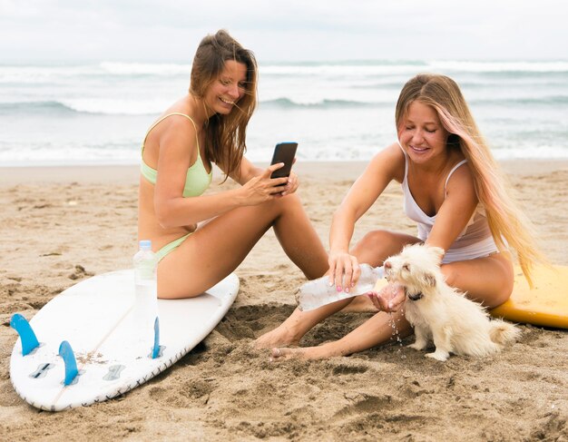 Подруги на пляже с собакой и смартфоном